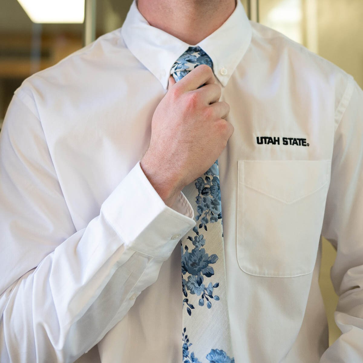 Young man wearing cream and blue floral boon tie with white utah state embroidered dress shirt